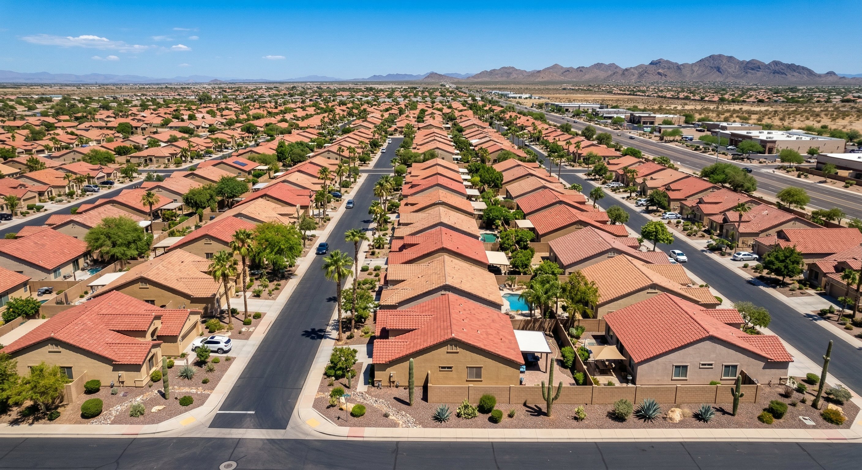 Aerial view of a Glendale, AZ neighborhood with stucco homes, tile roofs, and desert landscaping under a bright blue sky