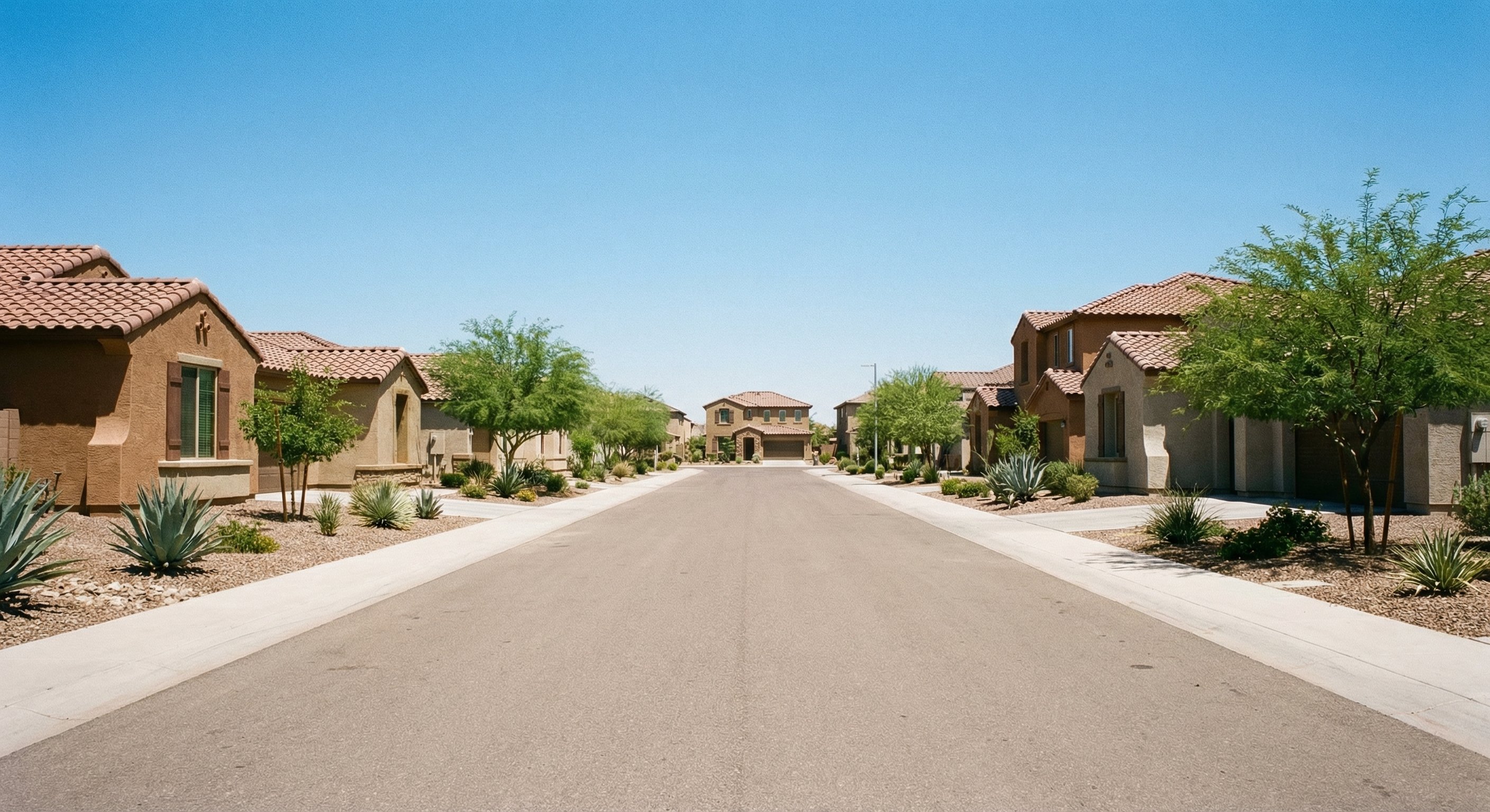 A quiet Maricopa Arizona suburban street with stucco homes and desert landscaping on a clear day